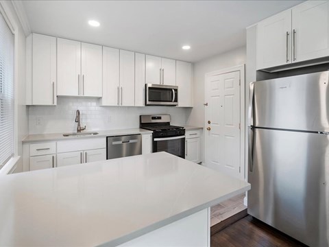 A kitchen with white cabinets and a stainless steel refrigerator.